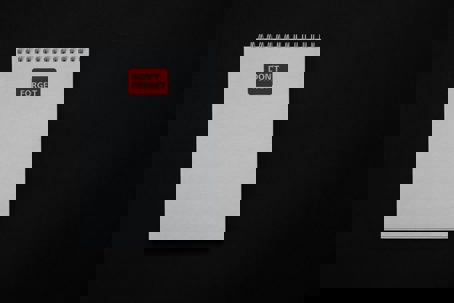 Blank spiral notepad on a black background with a red label reading “DON’T FORGET” at the top.